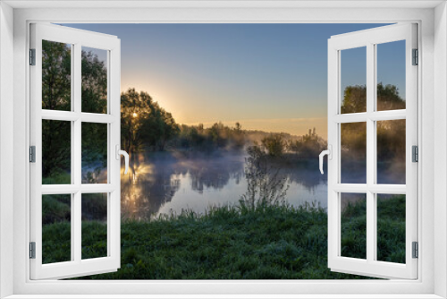 Fototapeta Naklejka Na Ścianę Okno 3D - Blue fog over the river, the rising sun reflected in the water, foggy morning in the countryside.
