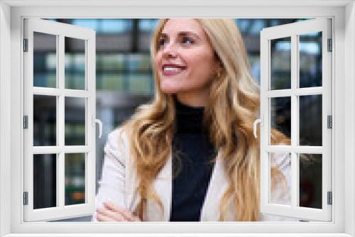 Vertical. Modern stylish Caucasian adult business woman dressed in formal suit standing in work place outdoor. Strong and empowered female happy with shaved head looking smiling to the side.