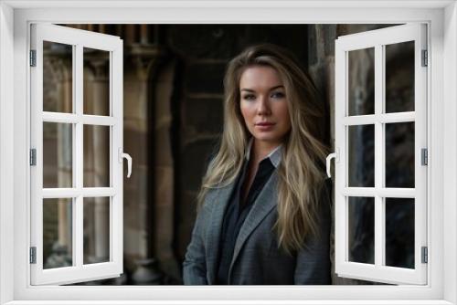 Confident woman in gray coat standing in front of stone building