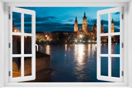 Riverside Radiance: Witnessing the Enchantment of Zaragoza's Twilight, with the Timeless Silhouettes of Basilica del Pilar and Stone Bridge Adorning the Skyline, Reflected in the Tranquil Waters of th