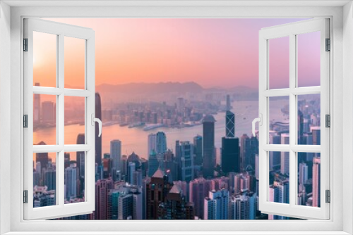 An aerial view of Hong Kong's skyline at sunset with a palette of warm hues highlighting the dense urban architecture against the backdrop of the harbor.