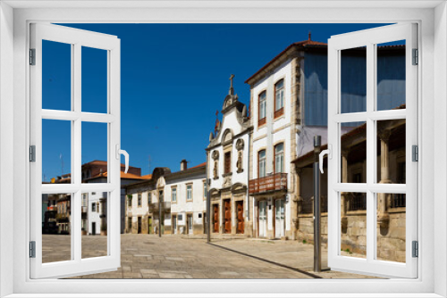 Fototapeta Naklejka Na Ścianę Okno 3D - View of residential houses and ancient Church of Mercy on typical paved street in old town of Mirandela in spring, Portugal.