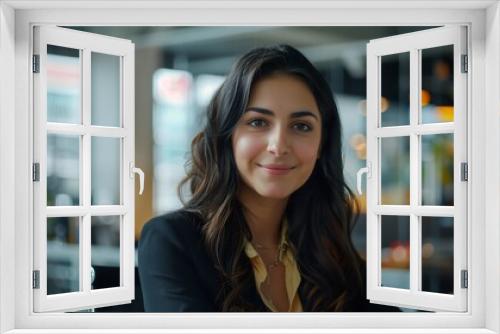 A dynamic businesswoman in a glass-walled office, sitting on a chair and looking directly at the camera with a determined look. 
