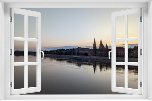 Fototapeta Naklejka Na Ścianę Okno 3D - View of Szeged at dusk, seen over an overflown Tisza river