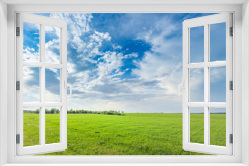 Fototapeta Naklejka Na Ścianę Okno 3D - A lush green field with vibrant trees reaching towards the sky, accompanied by billowing clouds in the background, creating a picturesque scene of tranquility and natures beauty.