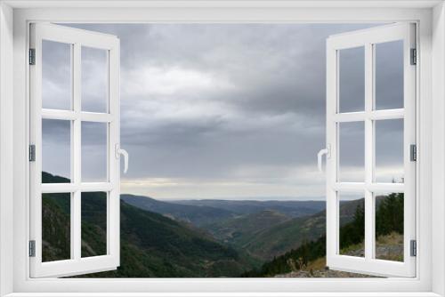 Fototapeta Naklejka Na Ścianę Okno 3D - The sky is cloudy and mountains are visible in the background. The mountains are covered with trees.