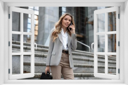 Full body photo of Caucasian female executive talking on cell phone on corporate steps.