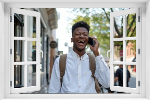 Excited young man having a pleasant conversation on his phone outdoors