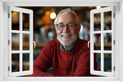 cheerful senior man with glasses, dressed in a red sweater, smiling in a coffee shop