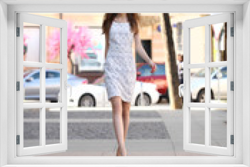 Beautiful young girl in white dress walking summer street