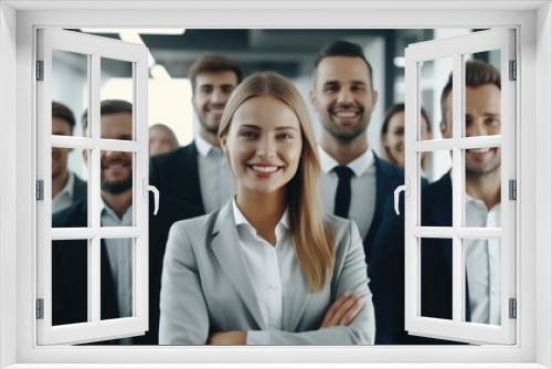 A group of people are smiling and posing for a photo. The woman in the center is wearing a suit and smiling