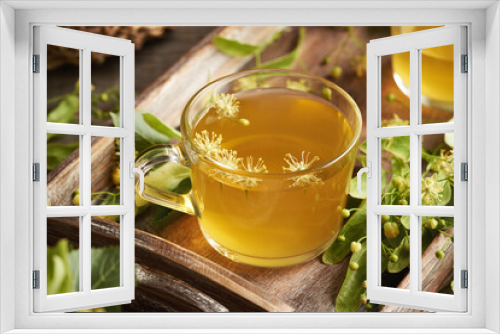 Fototapeta Naklejka Na Ścianę Okno 3D - A transparent cup of herbal tea with fresh linden or Tilia cordata flowers