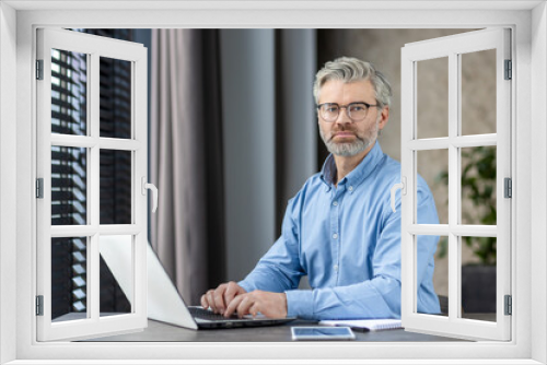 Professional businessman working on a laptop in a modern office. Mature individual demonstrating focus and productivity.