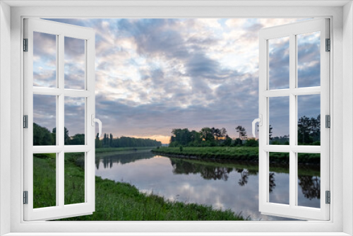 Fototapeta Naklejka Na Ścianę Okno 3D - Serene river landscape at dawn, with reflective water and cloudfilled skies, a peaceful scene of natures beauty