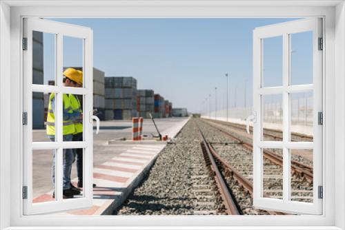 Workers in front of cargo containers near railway tracks on industrial site