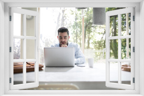 Young businessman sitting in office, using laptop