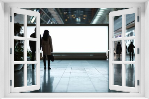 a couple man and a woman standing in-front of a big white mockup blank screen at a shopping mall or center - Generative AI 