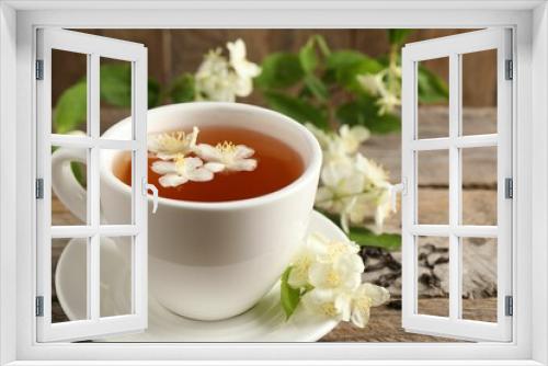 Fototapeta Naklejka Na Ścianę Okno 3D - Aromatic jasmine tea in cup, flowers and dry leaves on wooden table