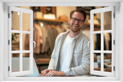 Smiling man with glasses working on laptop in a retail store.