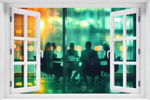 A group of people sitting around an office table in meeting room with glass walls and a green light in the background