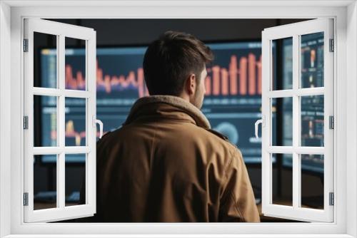 A man stands in front of three computer monitors displaying multimedia content