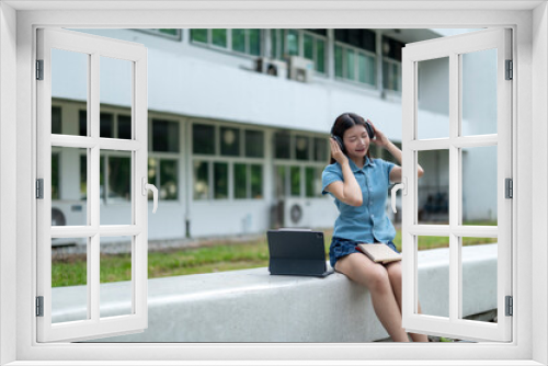 A woman is sitting on a bench with a laptop and a book