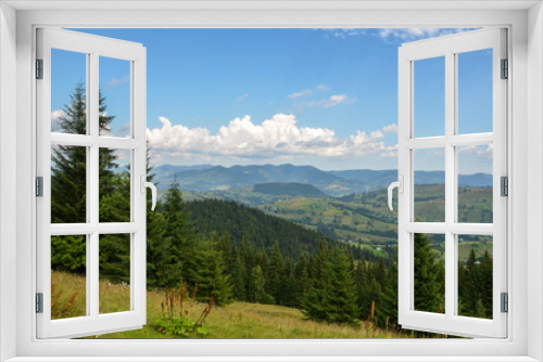 Rolling hills and mountains under a partly cloudy sky. Lush greenery in the foreground undulating hills in the middle ground and a distant mountain range create a serene natural landscape. Carpathians