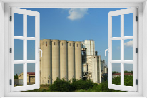 Fototapeta Naklejka Na Ścianę Okno 3D - Old factory with silo tanks for corn near river