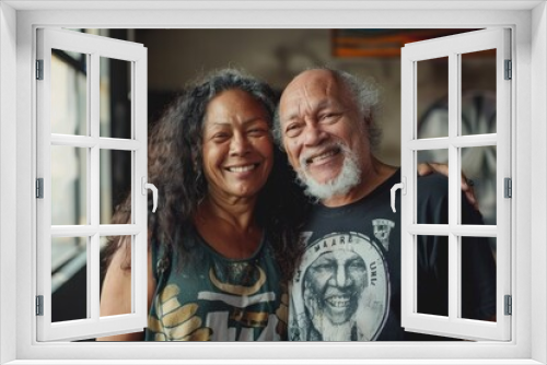 Portrait of a jovial mixed race couple in their 60s sporting a vintage band t-shirt in front of empty modern loft background