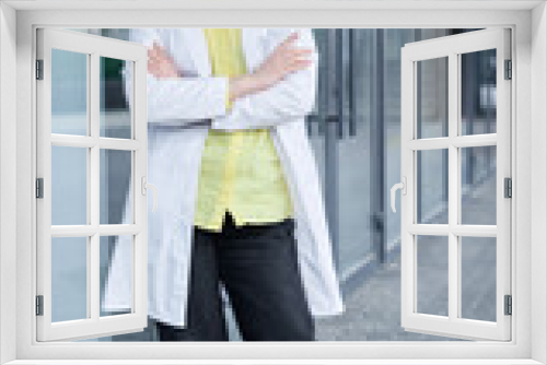 Positive female medical student in white uniform standing near clinic entrance and looking at camera smiling. Beautiful young blond doctor, veterinarian High quality photo