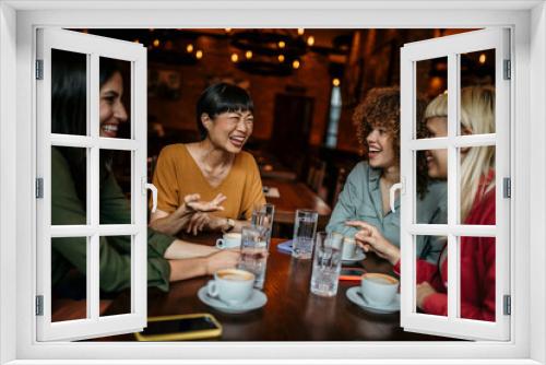 Group of smiling diverse females sitting in the restaurant, having a coffee and chatting