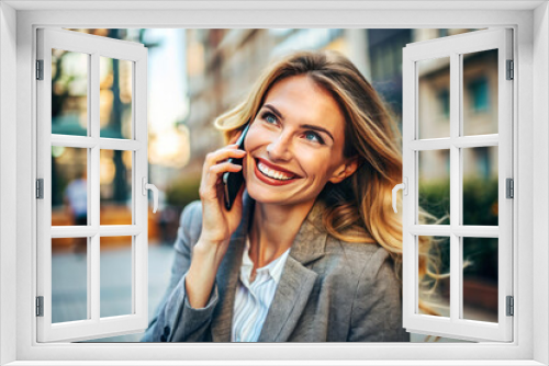 Smiling woman talking on the phone outdoors, wearing a blazer, with a joyful expression, capturing a moment of positive communication.