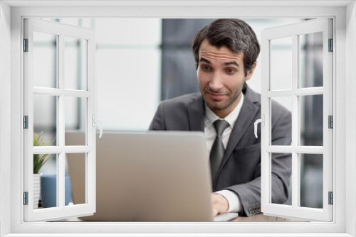 Excited businessman sitting at table with laptop and celebrating success