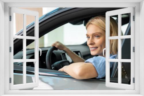 Blonde woman in a blue shirt sitting in a car and looking contented