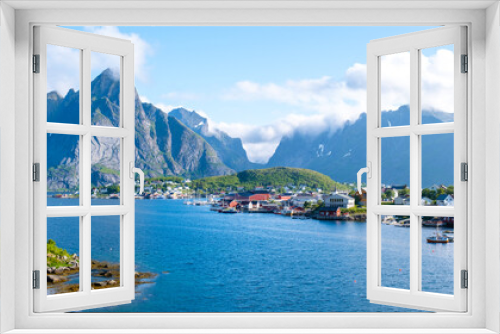 Fototapeta Naklejka Na Ścianę Okno 3D - Reine, Lofoten, Norway, village nestled between towering mountains in Norway. The clear blue waters of the fjord create a stunning contrast with the lush greenery and the traditional red houses.