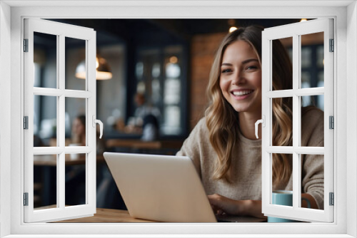 Happy young woman working on laptop computer and drinking coffee at coffee shop.