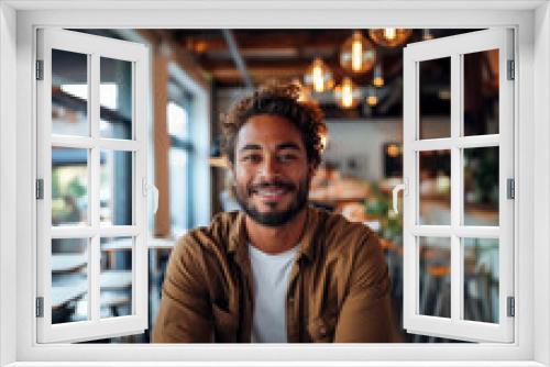 A stylish man with a beard happily smiles in a trendy cafe with a chic atmosphere and modern design