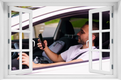 Young man male sit in the car use mobile phone for sms while drive car