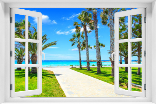 Fototapeta Naklejka Na Ścianę Okno 3D - A view of a azzure water and entrance to the beach with palms