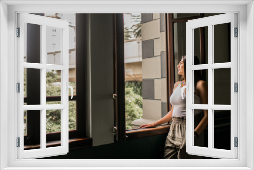 mujer joven en una ventana mirando afuera 