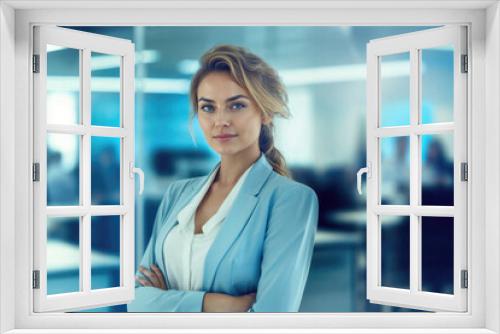 A woman in a blue suit stands in front of a window with her arms crossed