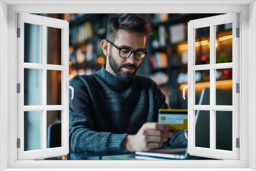 African American man sitting background modern interior holding credit card her hand, web laptop