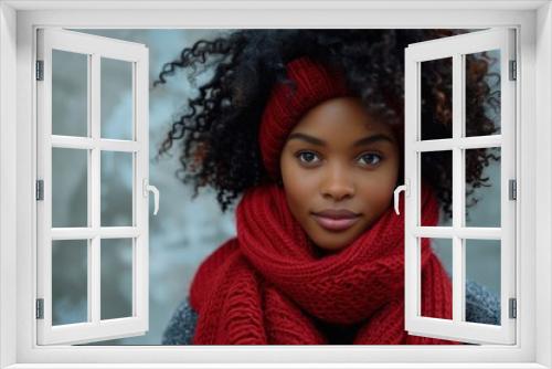 Black woman in red winter scarf and headband posing against grey wall