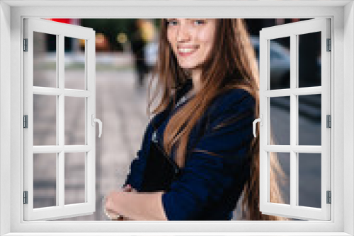 Successful businessman smiling, standing on the background of buildings and holding a tablet computer. City business woman working.