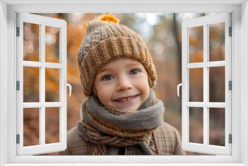 cheerful child with scarf and hat smiling in autumn forest