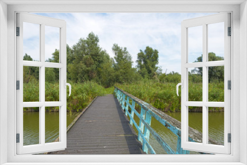 Fototapeta Naklejka Na Ścianę Okno 3D - Wooden footbridge over a canal in summer