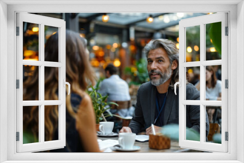 Middle-aged man with long gray hair and a beard having a conversation with a woman in an outdoor café