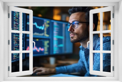 A man is sitting in front of two computer monitors