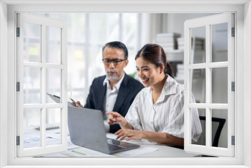 Two people are sitting at a desk with a laptop open