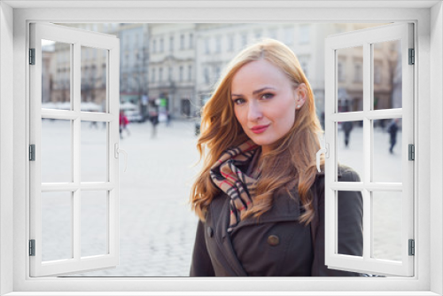 Beautiful blonde happy woman walking on the street in city. Outdoor photo.